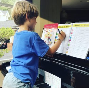 Young boy practicing piano with the cascade method workbook 