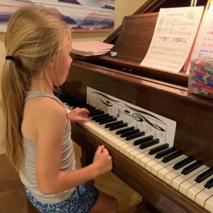 A young girl is playing piano the fun way by using notematch