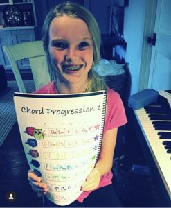 Young girl holding up her Cascade Method Piano Theory Book