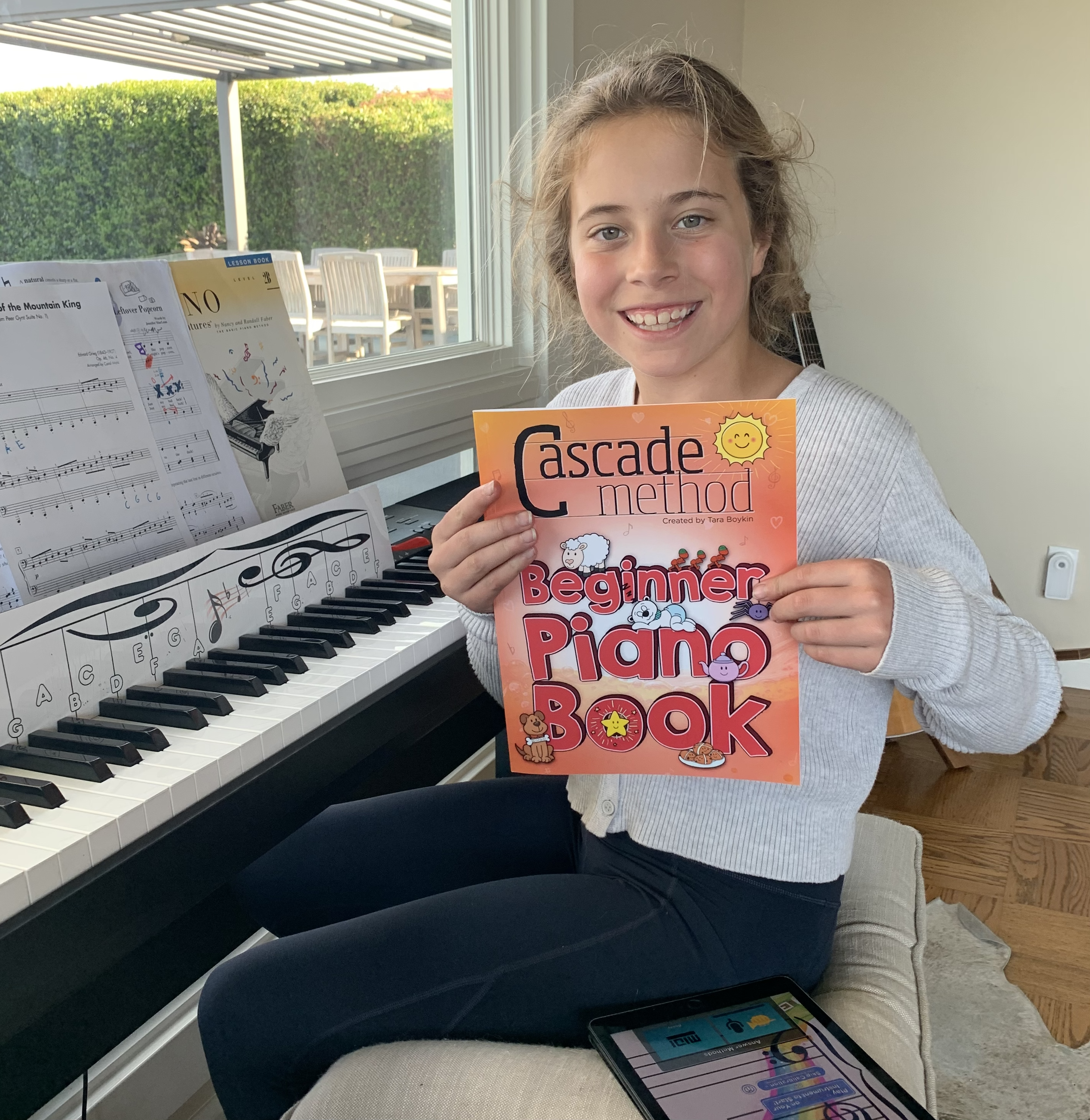 Girl student holding up the Beginner Piano Book