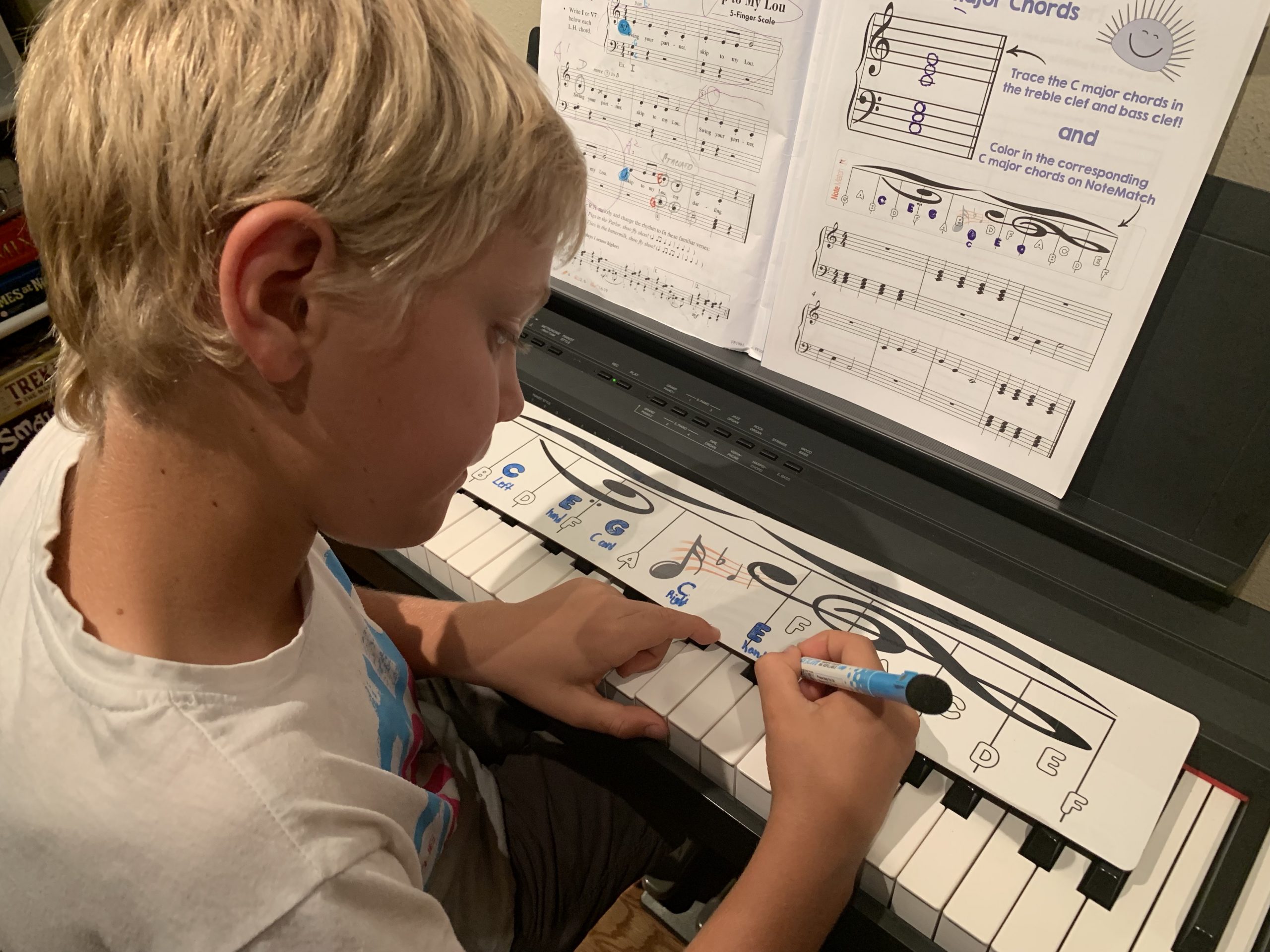 Young boy coloring in piano notes on the life-sized NoteMatch while learning about chords