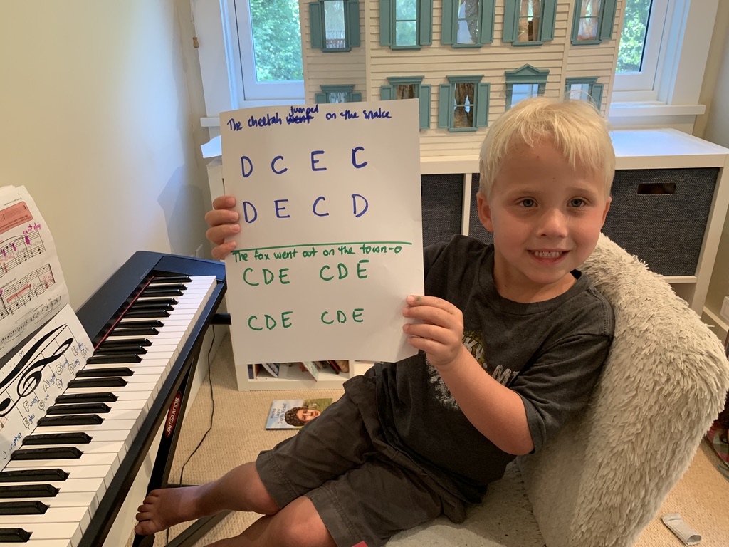 Young boy showcasing his worksheet during piano lessons